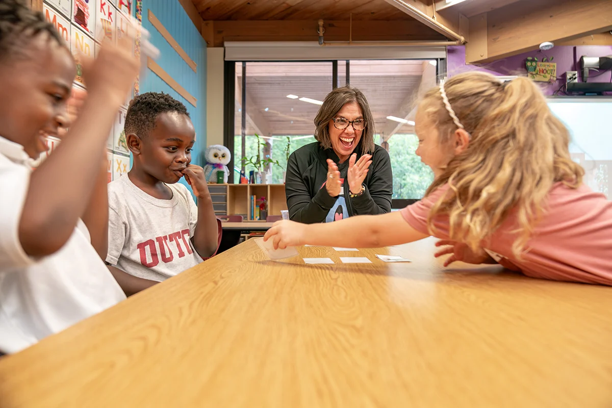 Teacher at a table clapping during the 5 Senses Fair