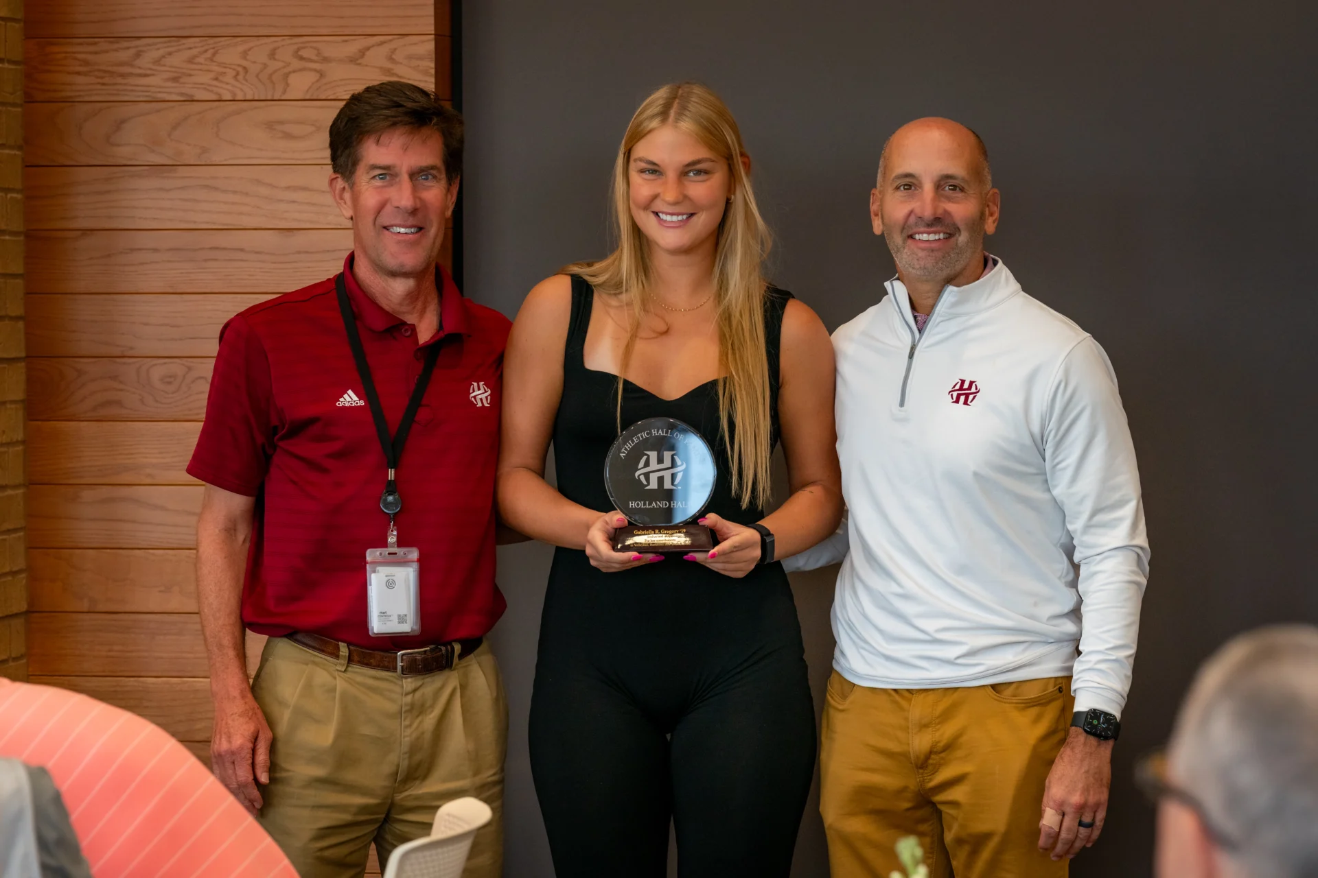 Former student, coach and athletics director posing for picture at the Athletic Hall of Fame.
